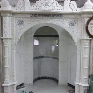 Supplier reference photograph of the white marble mosque qibla with carved columns, a broad arch, inscription panels and an ornamental crown