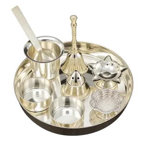 Silver-colour pooja thali gift set with bell, glass, spoon, bowls and devotional accessories on a transparent background