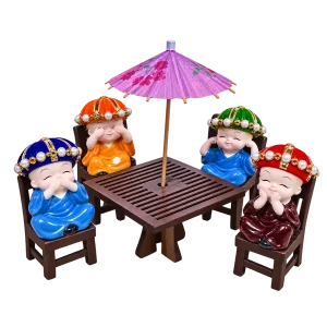 Four mini monk figurines with wooden table chairs and purple umbrella on a transparent background